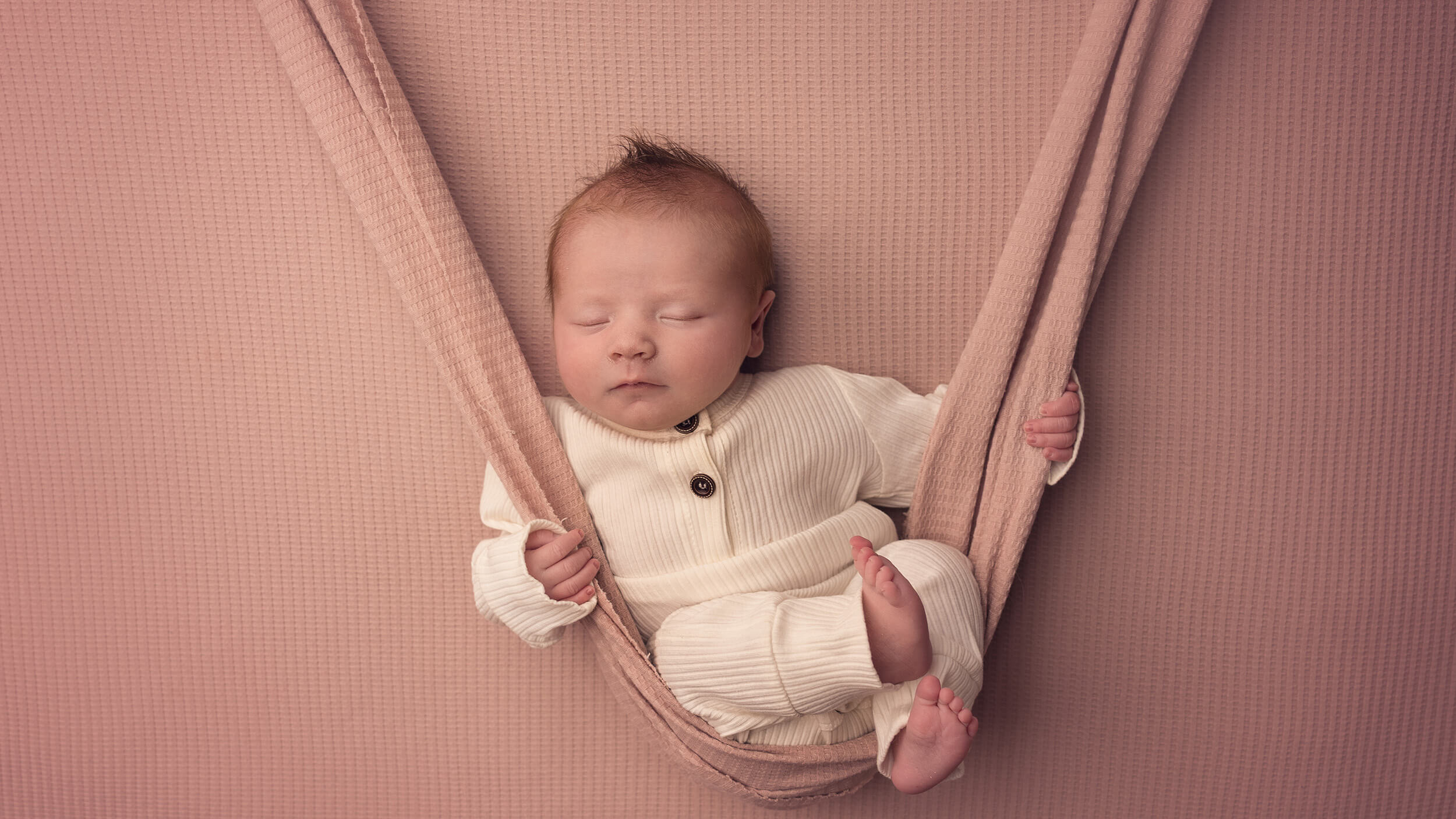 a newborn baby girl in a swing at a photoshoot in Bodmin studio