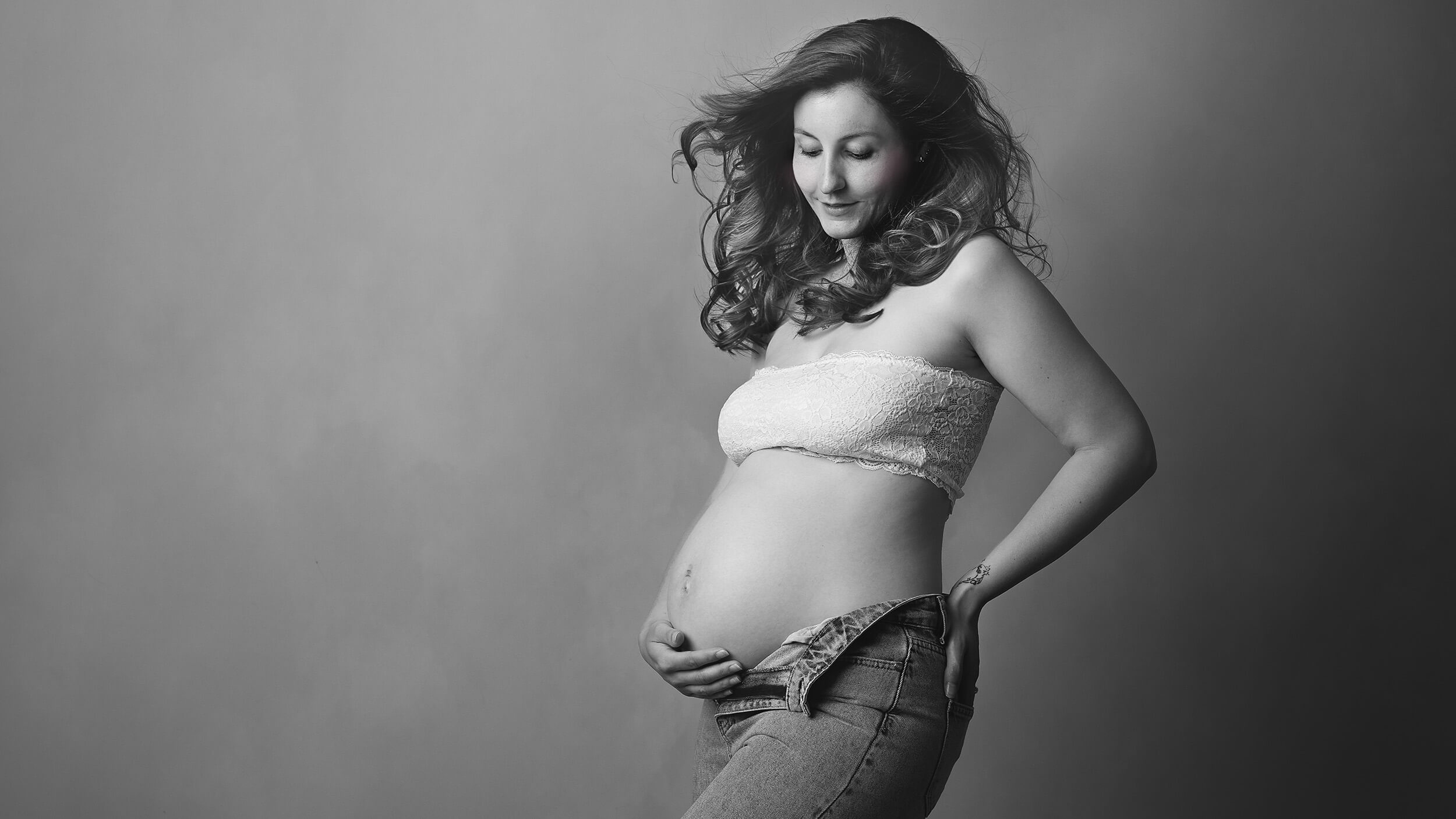 Pregnant woman holding her bump at a maternity photo shoot with AnA Photography in Cornwall