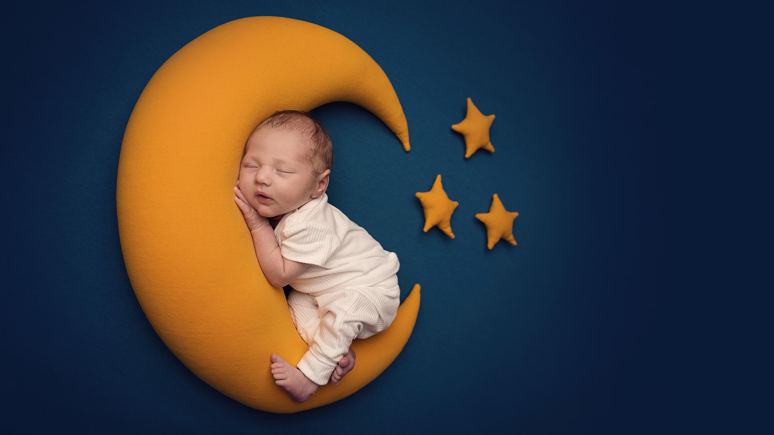 a newborn baby posed with a moon and starts cushion at a photo shoot in Cornwall with AnA Photography.