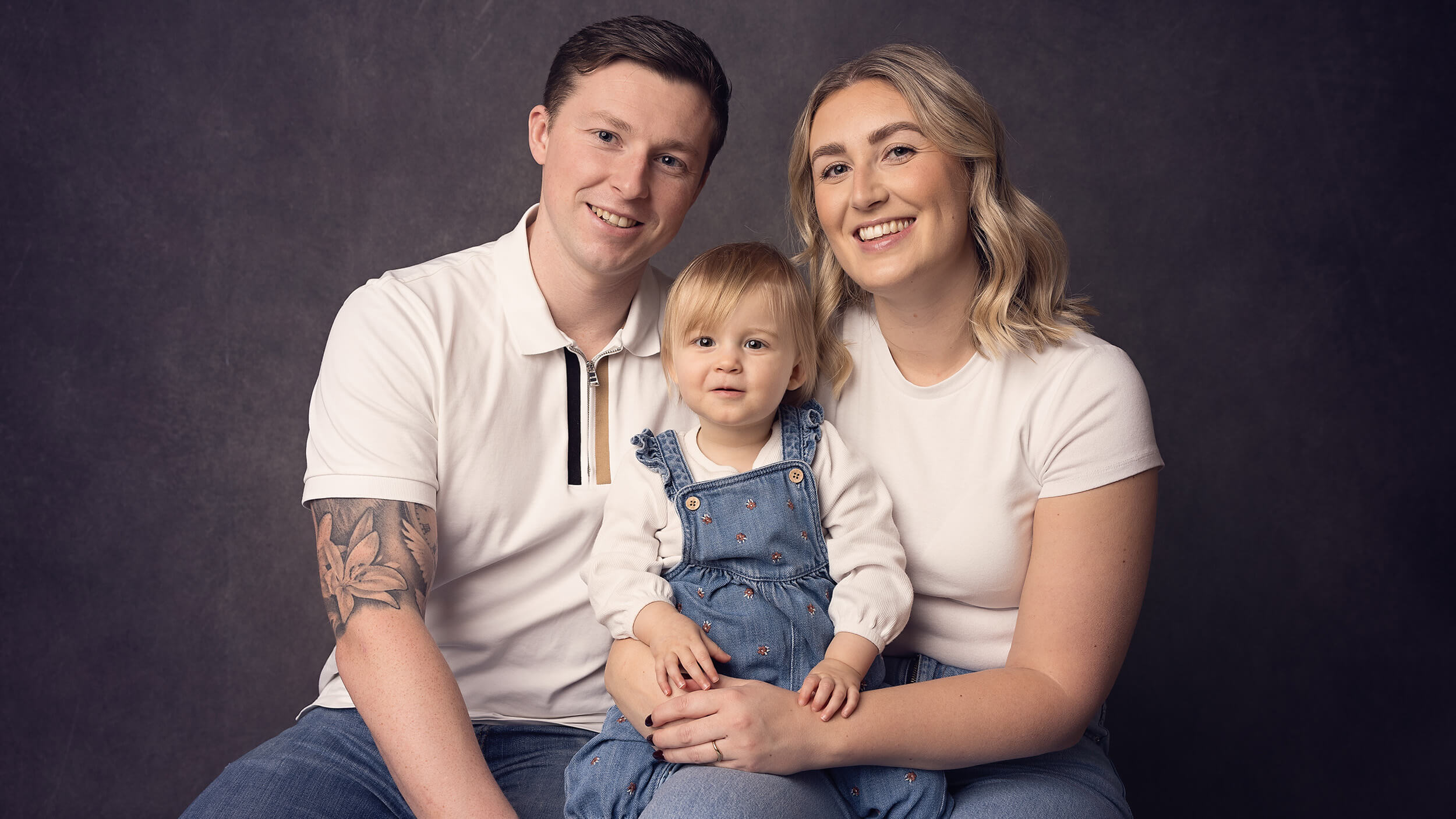 A family photo with Mum, Dad and a toddler girl posed for AnA Photography.